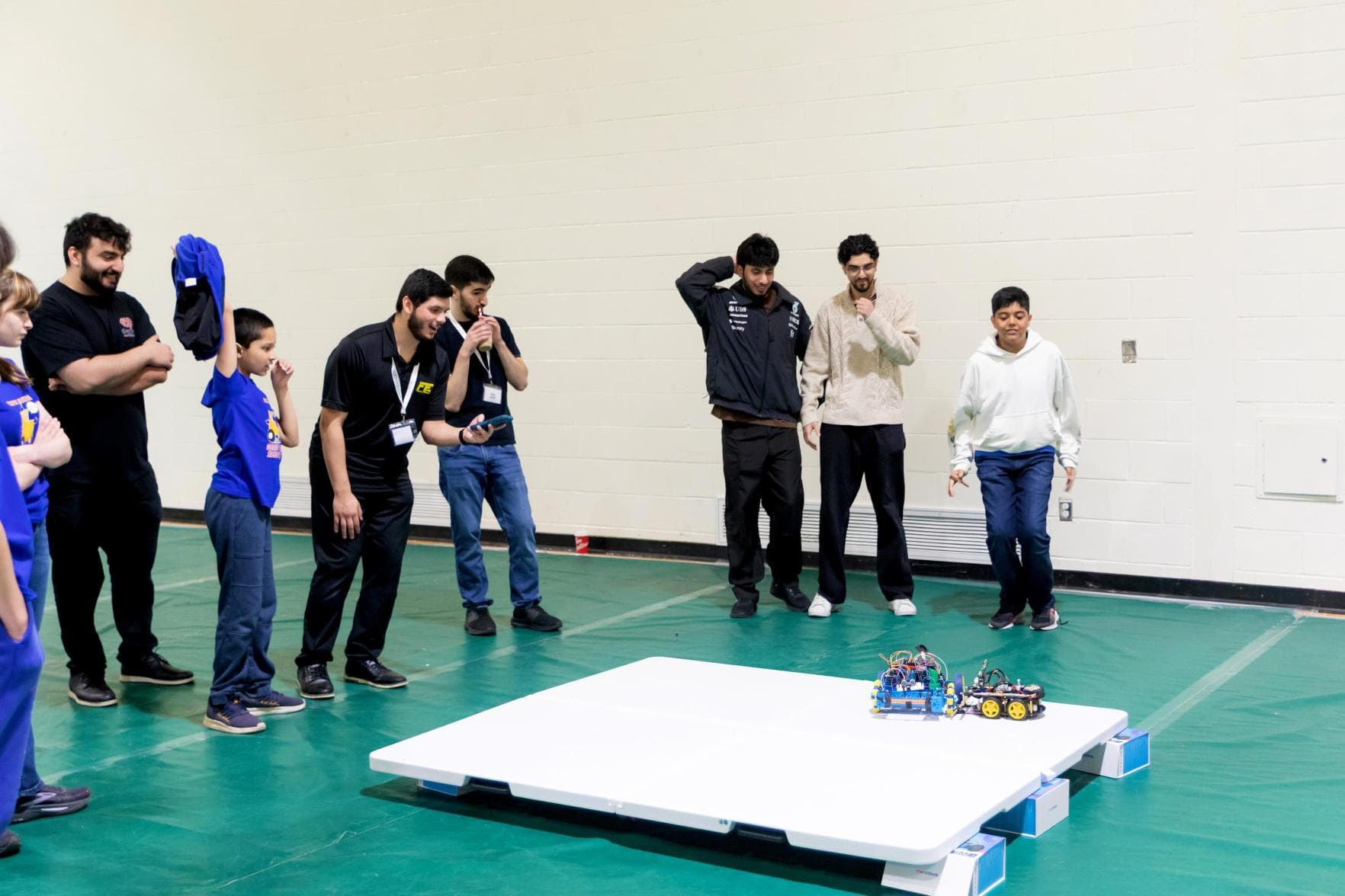Ahmad refereeing a robot battle at the Genius Cup as students watch
